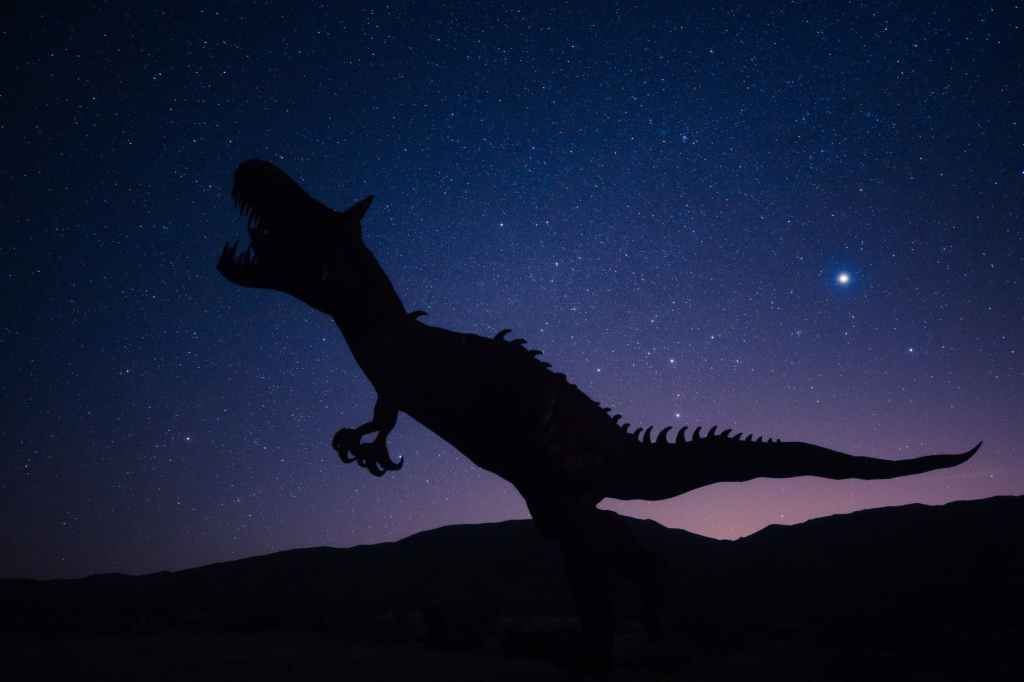 A carnivorous dinosaur silhouetted against a night sky.